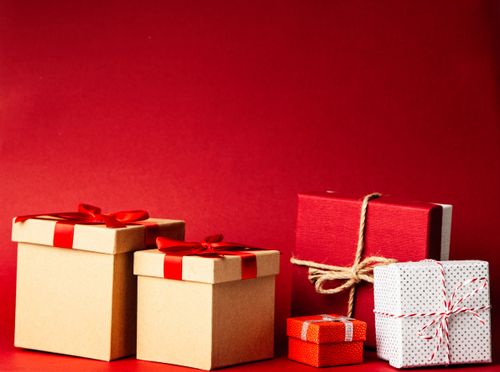 Free A collection of colorful gift boxes with ribbons on a rich red background, perfect for holiday themes. Stock Photo