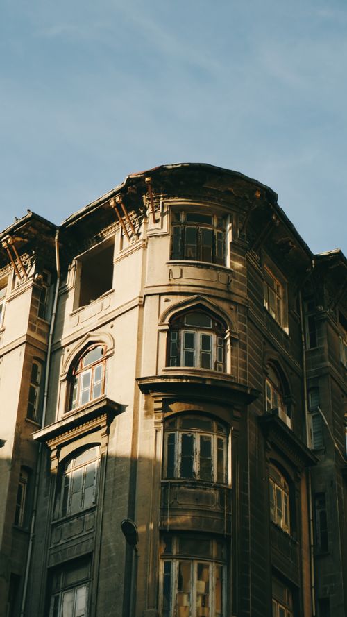 Free Vintage tenement building with intricate facade and arched windows against a clear blue sky. Stock Photo