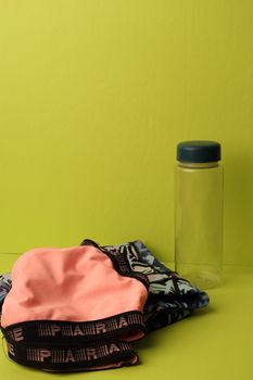 Minimalist shot of a water bottle and clothing against a yellow background.