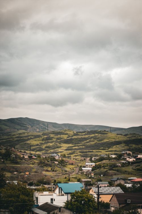 Free Picturesque village with rolling hills under an overcast sky, captured vertically for a classic look. Stock Photo