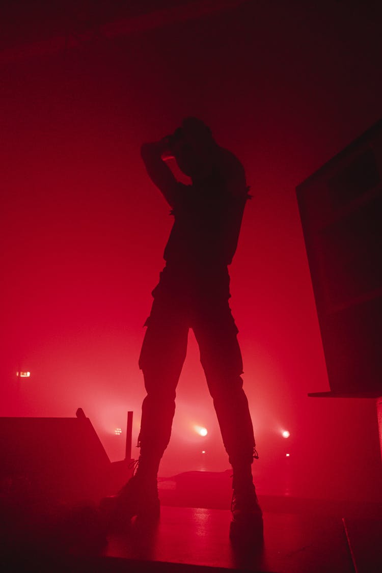 Silhouette Of Man Standing On Stage In Red Spotlight