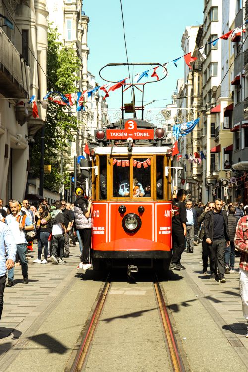 Free Colorful tram navigating through a busy street in Istanbul, surrounded by pedestrians and festive decorations. Stock Photo