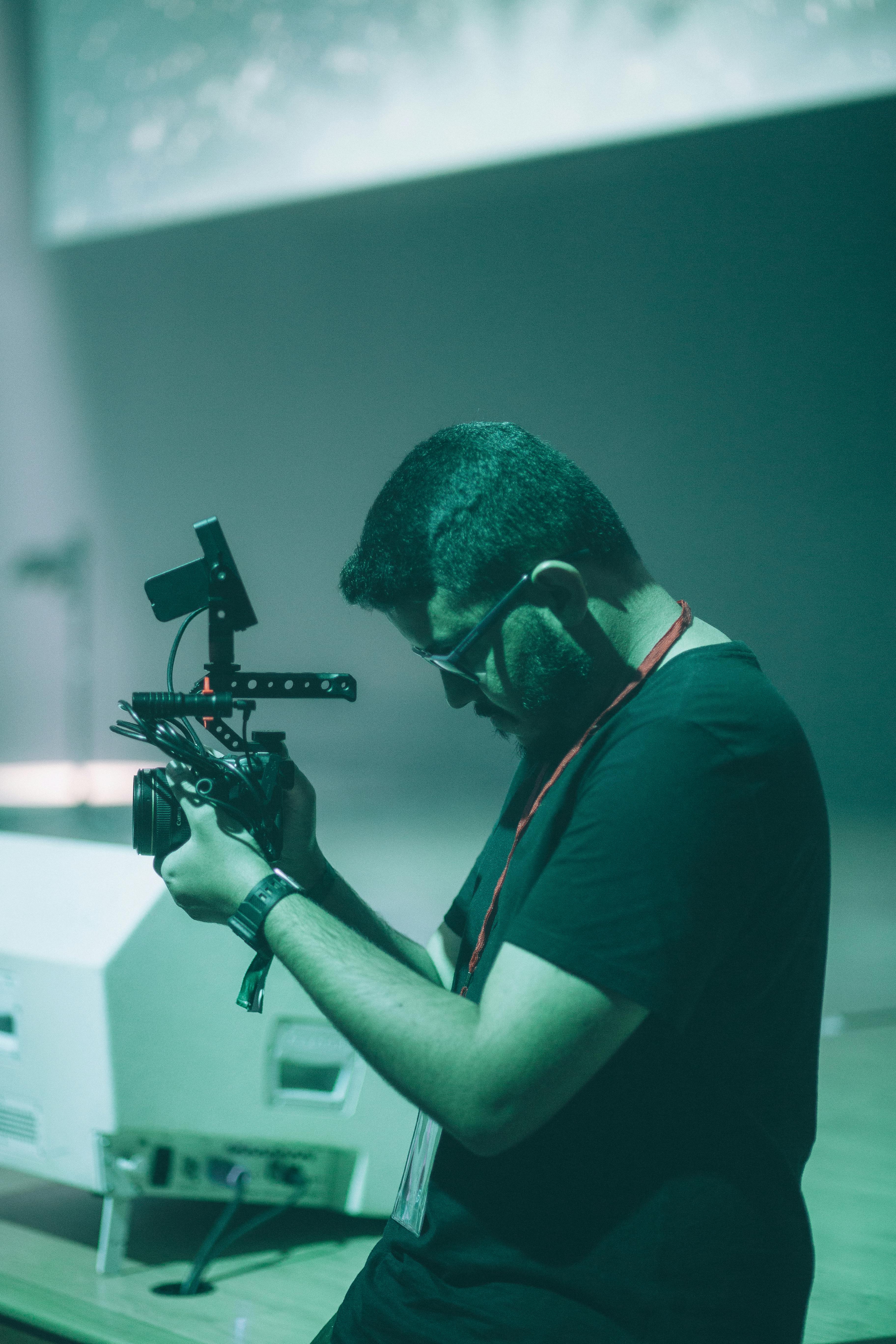 A focused man using a professional camera setup while filming indoors on a set.