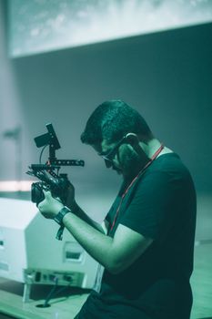 A focused man using a professional camera setup while filming indoors on a set.