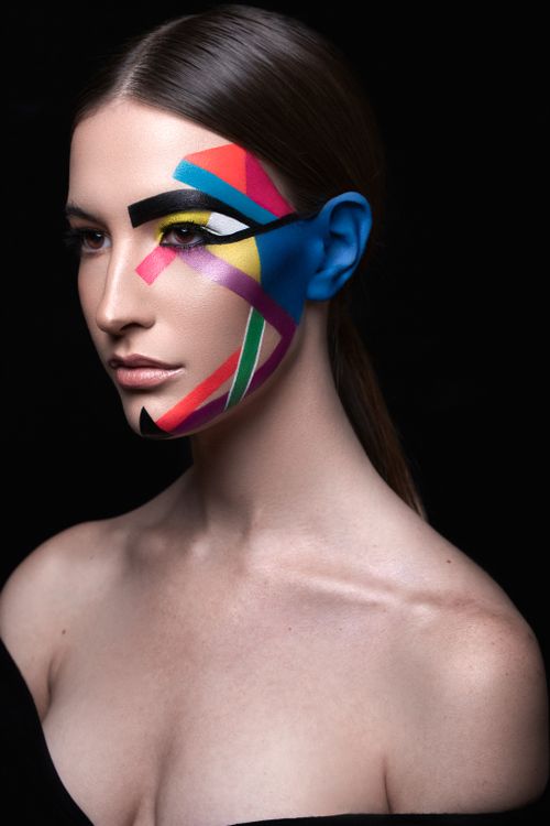 Free Artistic portrait of a woman with vibrant geometric face paint on black background. Stock Photo
