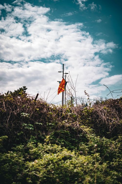 Free Macedonian flag waving on a hilltop under a dramatic cloudy sky, symbolizing national pride. Stock Photo