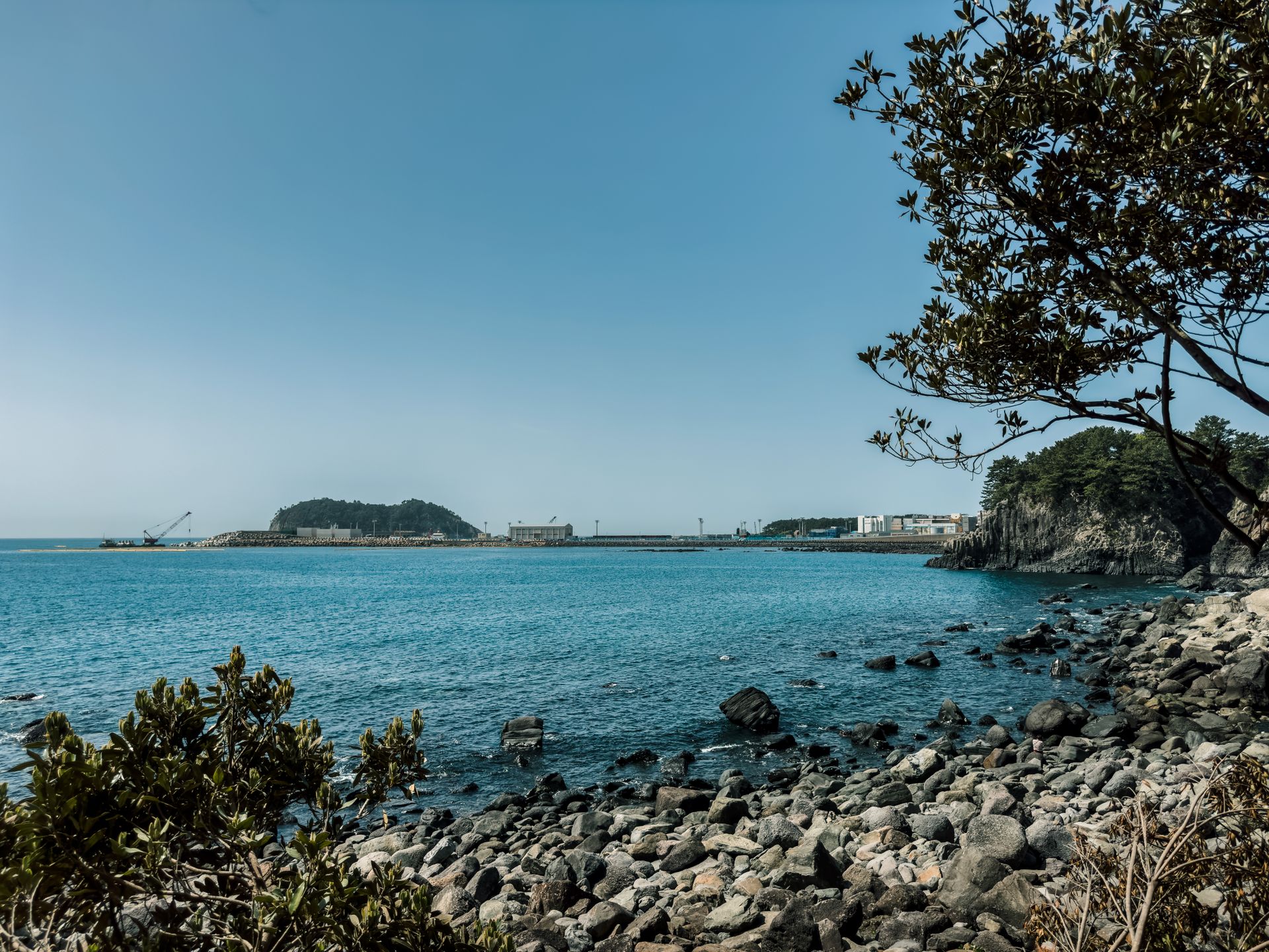 Serene coastal landscape of Jeju Island with clear blue sky and tranquil sea, ideal for travel and nature lovers.