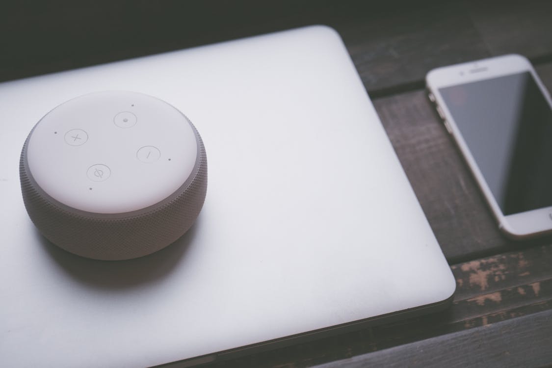 Free A smart speaker, laptop, and smartphone array representing modern technology lifestyle on a wooden surface. Stock Photo