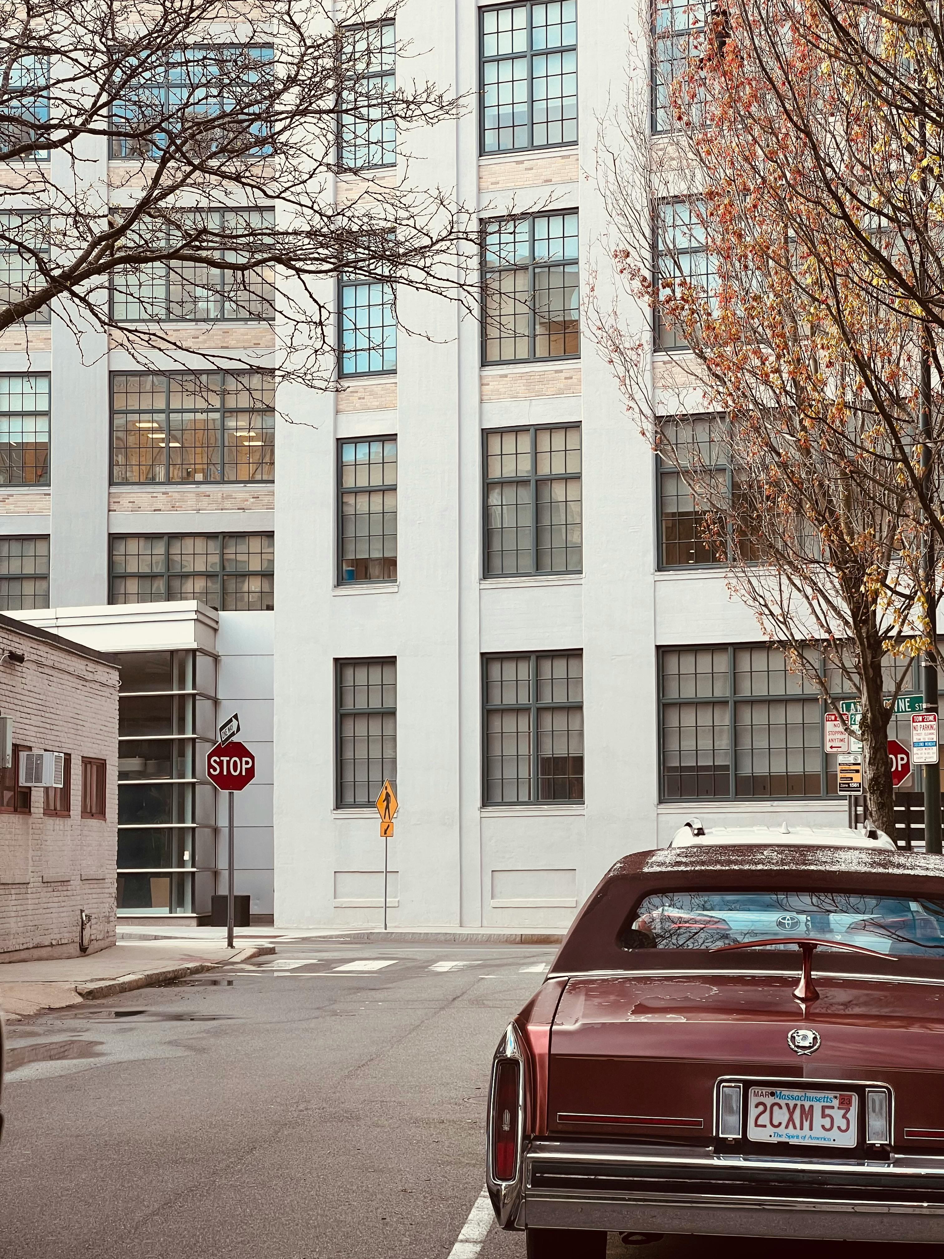Free A vintage car parked on a city street beside an old office building. Stock Photo