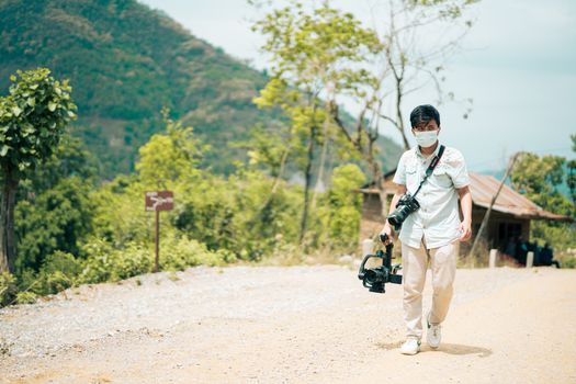 Outdoor portrait of a photographer walking a rural path in Gandaki Province, Nepal, with camera gear.