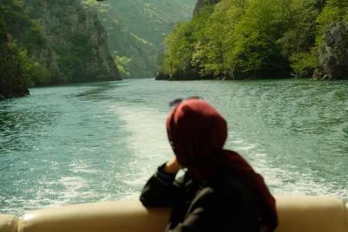 Free Woman in hijab enjoys scenic boat ride on a river in North Macedonia's canyon. Stock Photo