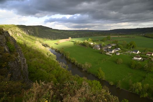 A tranquil rural scene featuring a village, lush fields, and a winding river.