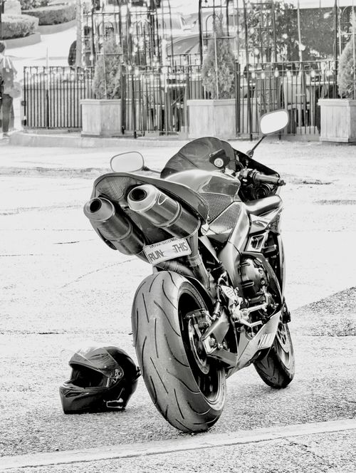 Free Black and white photo of a motorcycle parked on city pavement with a helmet. Stock Photo