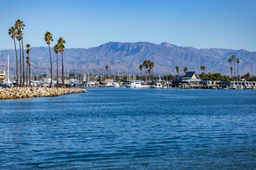 Beautiful view of Channel Islands Harbor in Oxnard, CA with palm trees and mountains in the background.