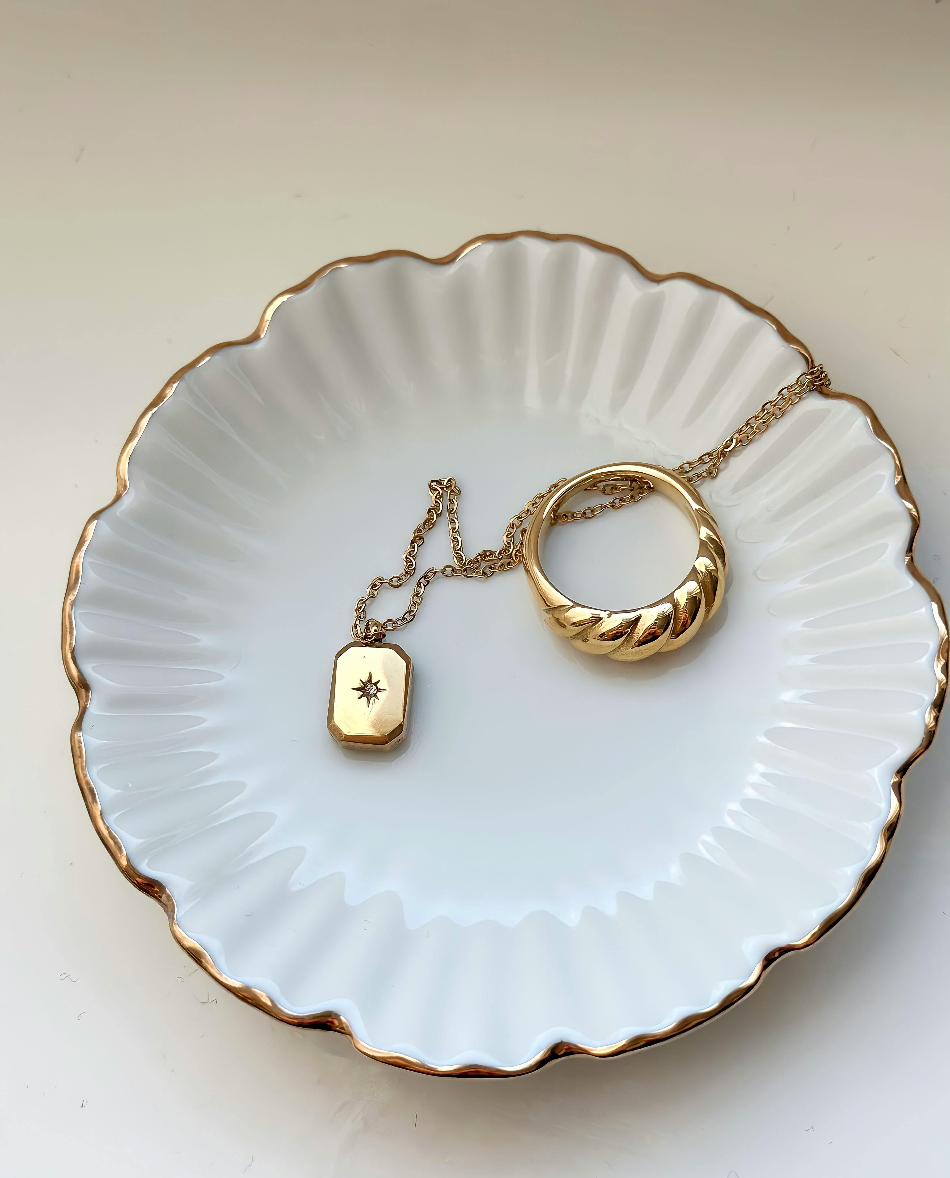 gold ring and necklace lying on porcelain plate