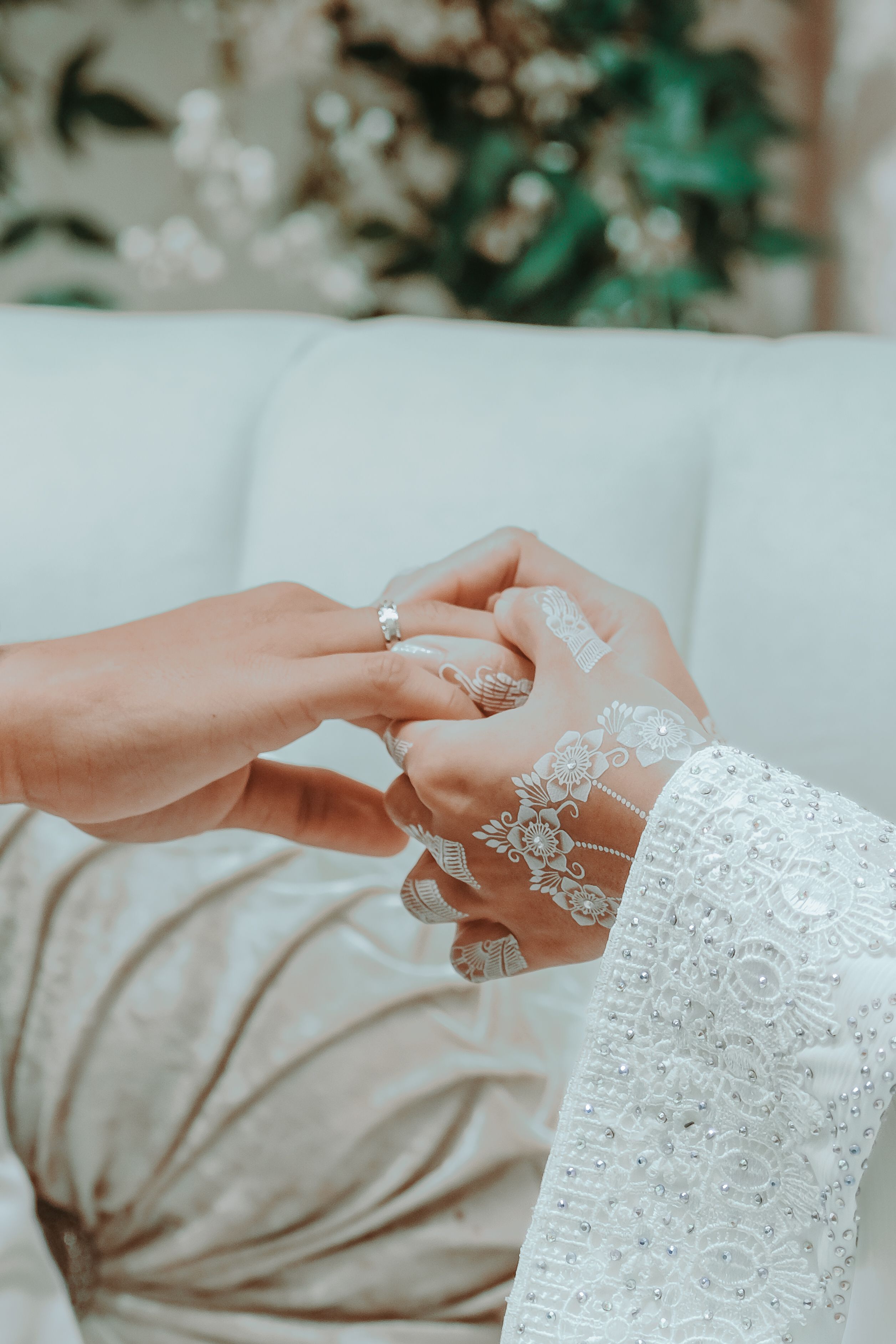 Close-up of a bride and groom exchanging rings, featuring intricate henna and elegant bridal attire.