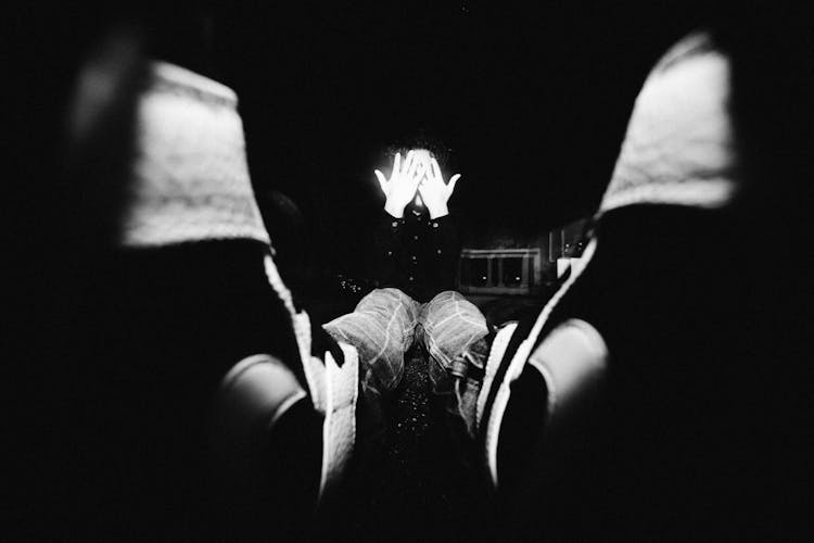 Black And White Photo Of Man Sitting On Ground Covering Face With Hands