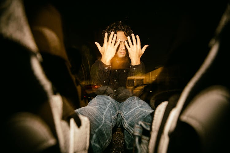 Man Sitting On Floor Covering Face With Hands