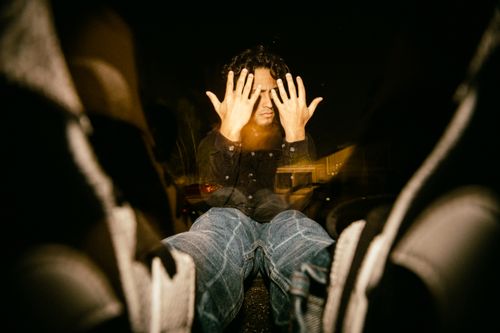 Free A man sits indoors with hands covering face, creating a moody reflection. Stock Photo