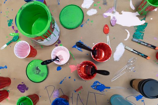 Top view of a colorful painting workspace featuring paint cans, brushes, and various paint colors on cardboard.
