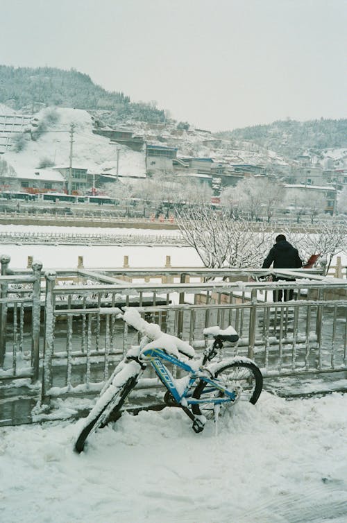 Free A lonely bicycle blanketed in snow near a frozen river during winter. Stock Photo