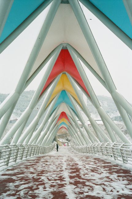 A vibrant geometric footbridge with snow-covered walkway in winter season.