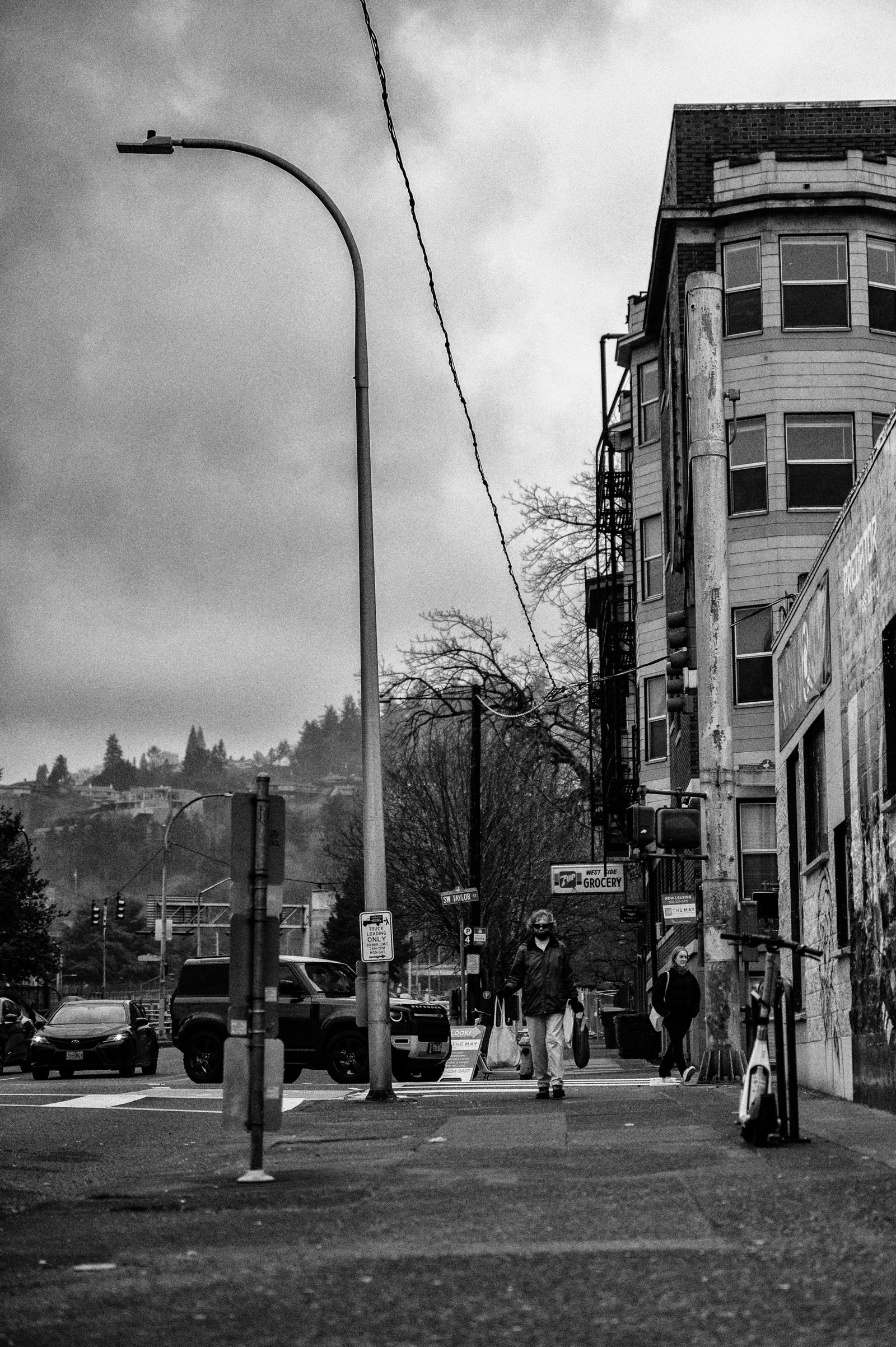 Black and white street scene with pedestrians walking past building facades
