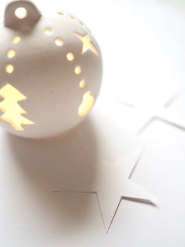 这款白色圣诞装饰品，灯光柔和优雅，饰有星星和树木的雕刻，营造出宁静的节日氛围