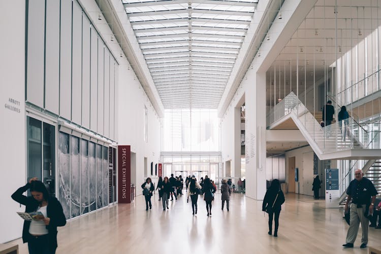 People Along Hallway Of Concrete Building