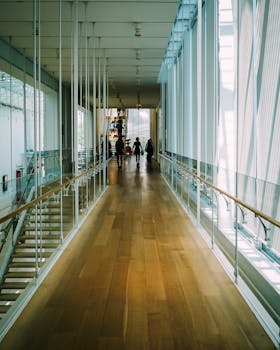 现代化的室内走廊铺着木地板和玻璃栏杆，捕捉到一群人行走的场景