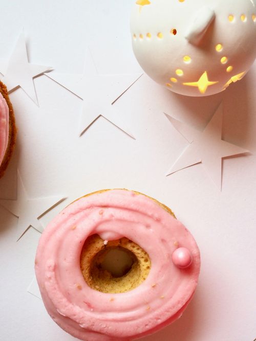 Free A close-up of a pink frosted donut with a decorative lantern and star cutouts in the background. Stock Photo