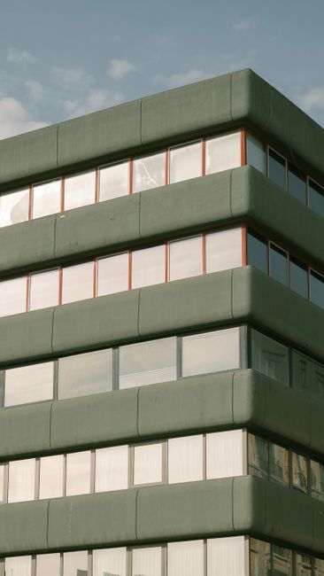 A contemporary building with geometric design and reflective glass windows under a clear sky.