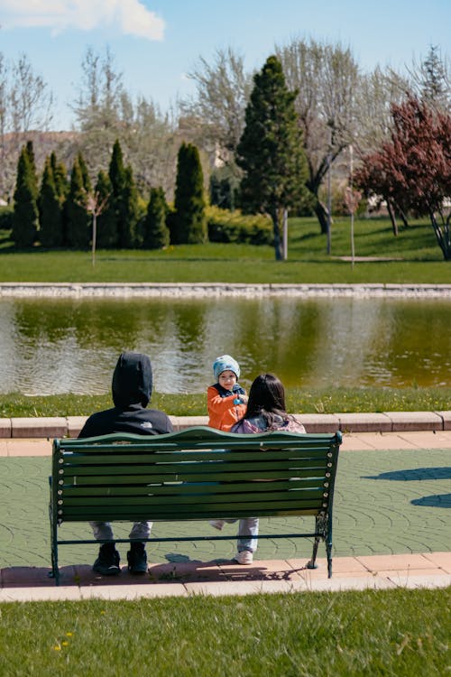 Mother and Father Sitting with Child on Bench in Park