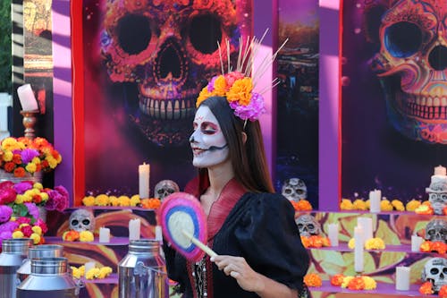 A woman in a sugar skull costume holding a lollipop