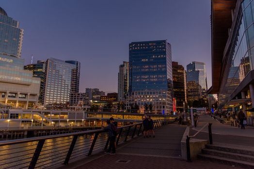 Urban scene at dusk in Vancouver, BC featuring modern waterfront architecture and city skyline.