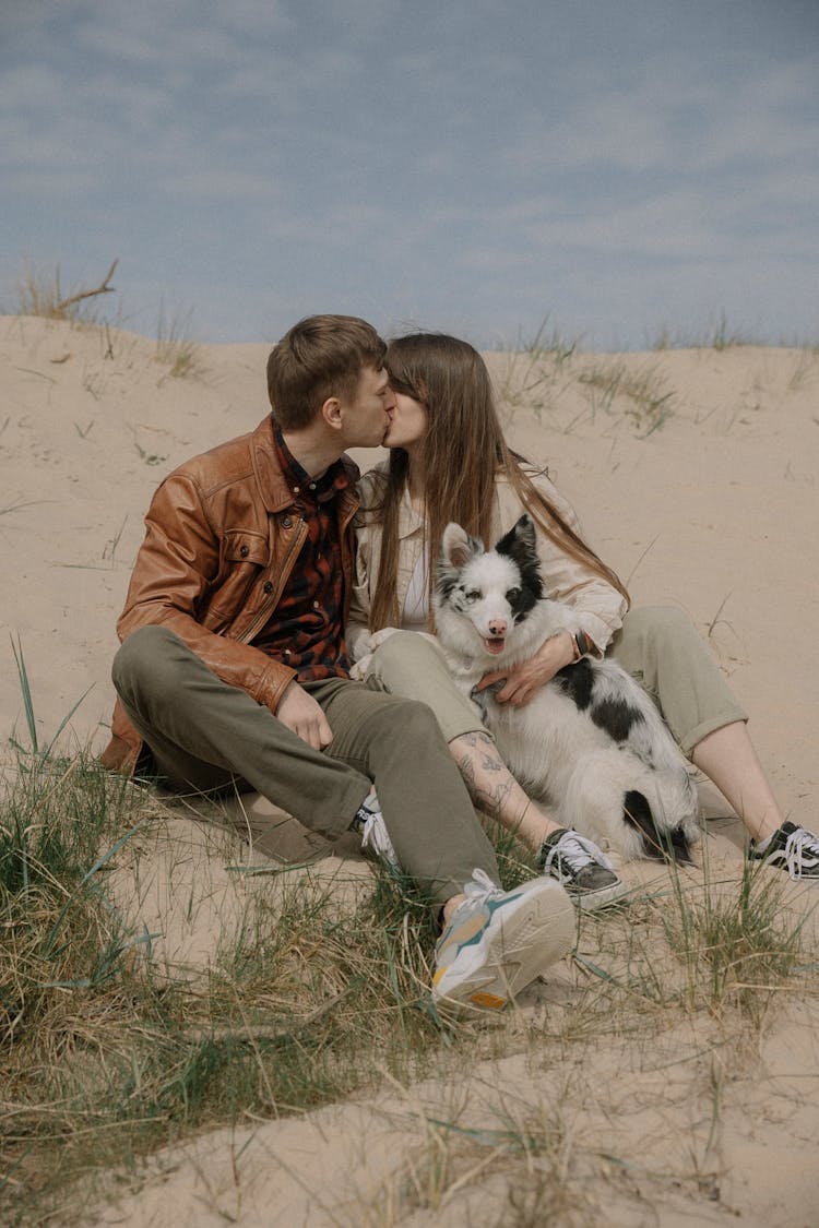 Couple With Dog Kissing At Beach