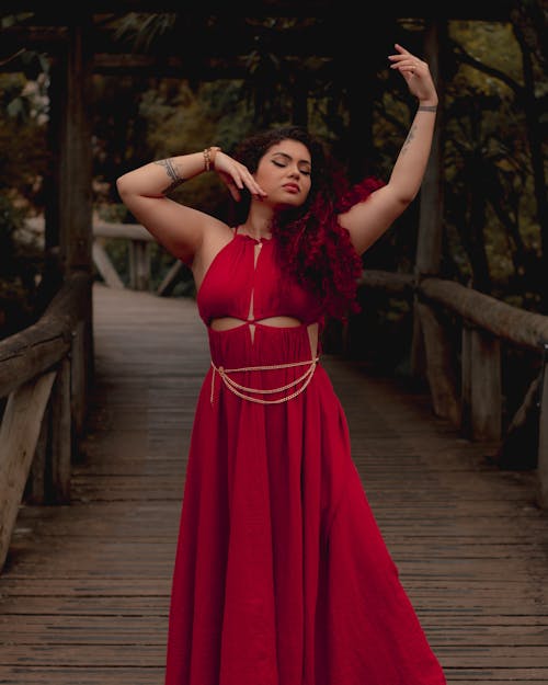Young Woman in a Long Red Dress Posing Outdoors 