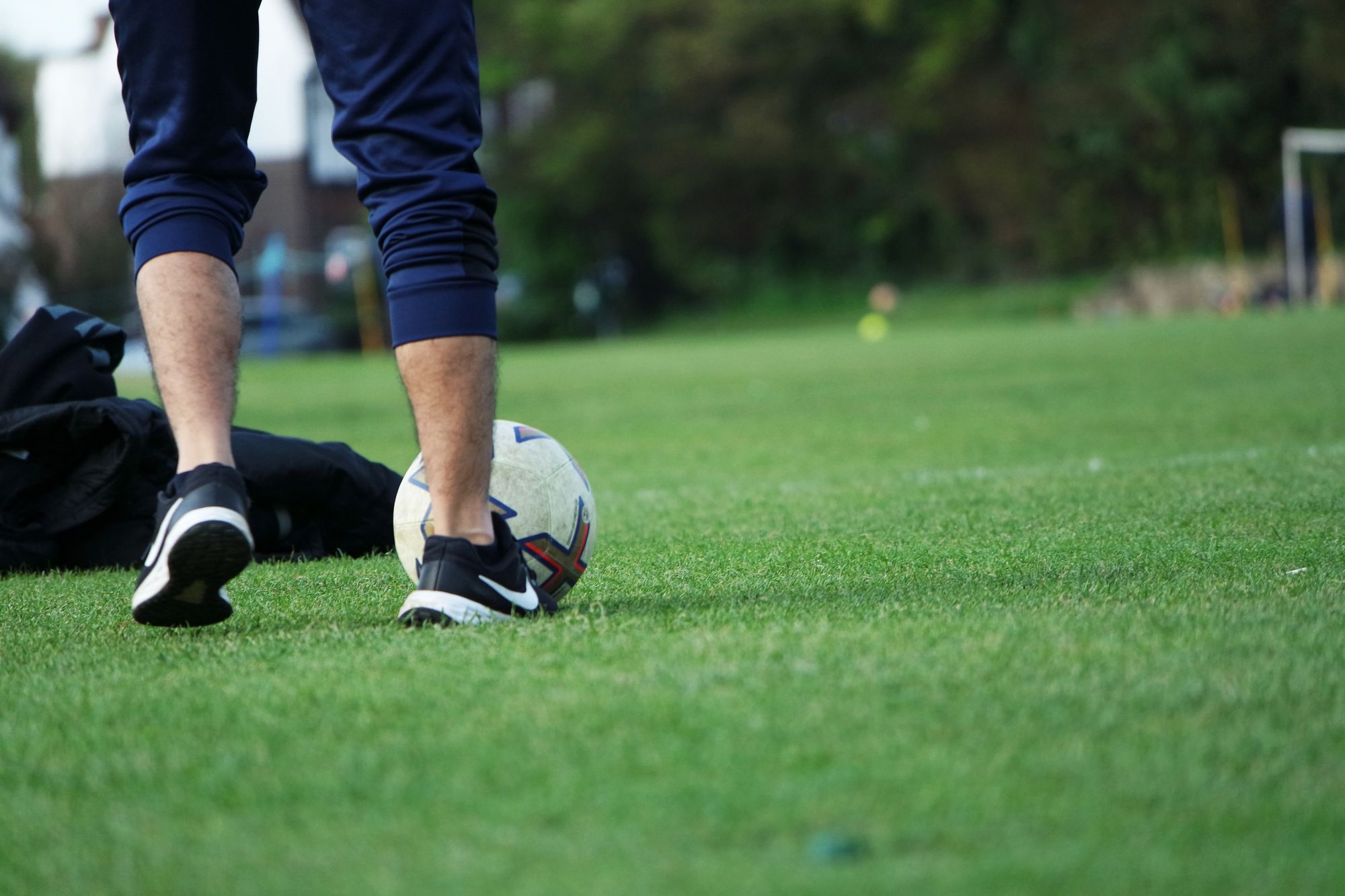 Futbolista con balón durante una sesión de entrenamiento en un campo de césped