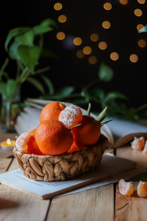 Free A woven basket with fresh juicy tangerines on a rustic wooden table, creating a warm and cozy atmosphere. Stock Photo