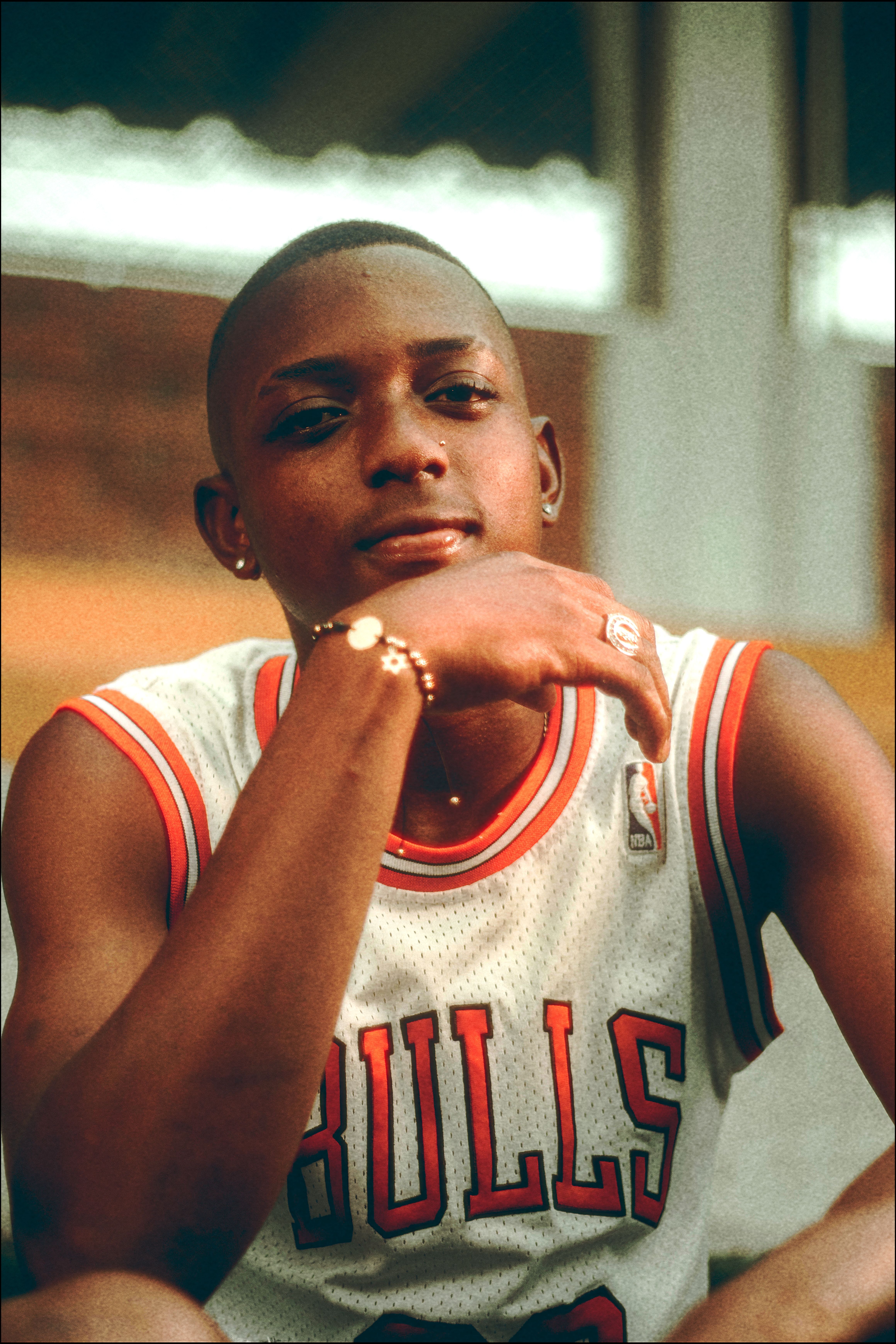 Portrait of a young basketball player in a Bulls jersey seated outdoors, looking at the camera.