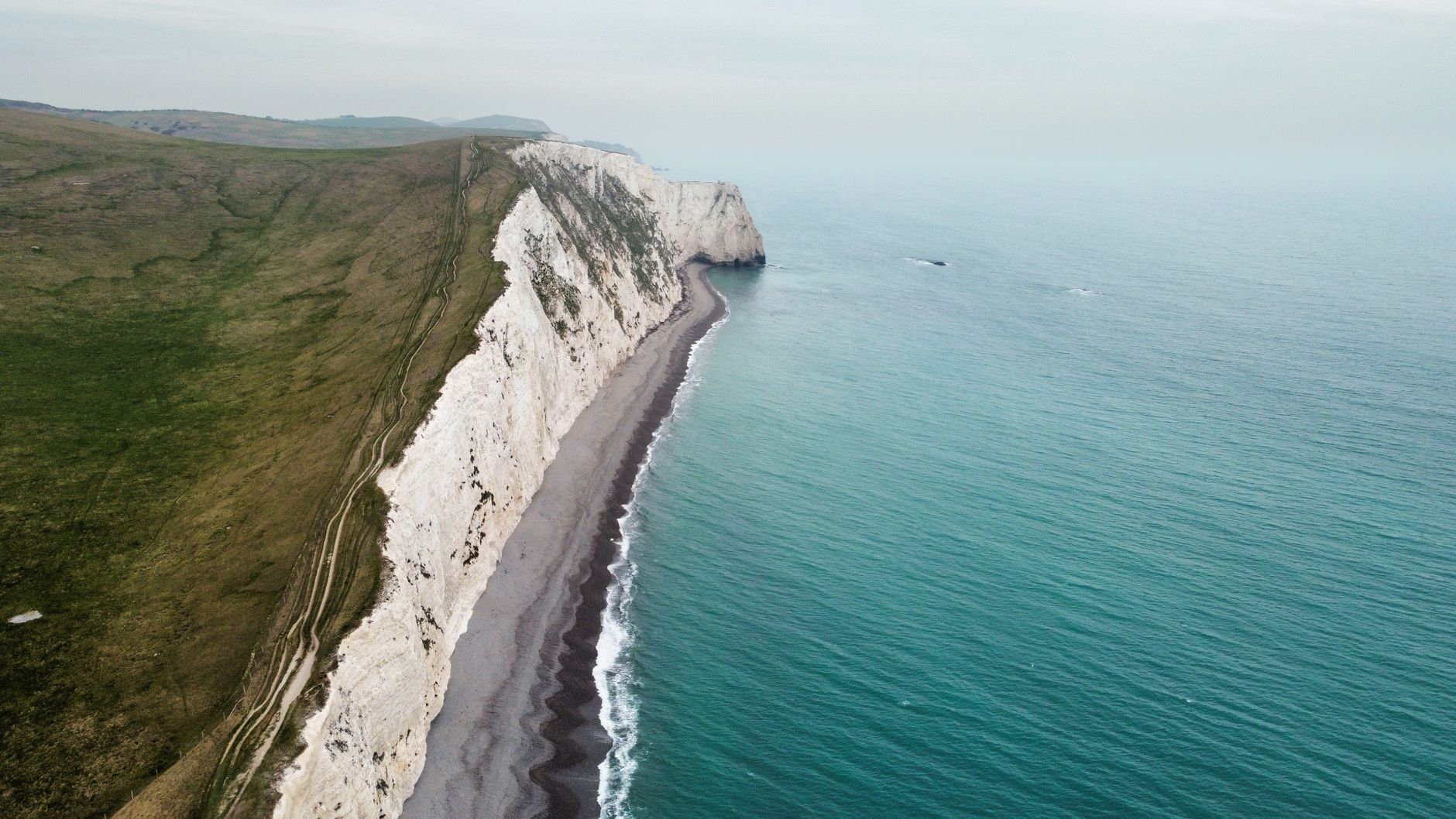 Breathtaking aerial view of Dorset's Jurassic Coast cliffs and turquoise waters.