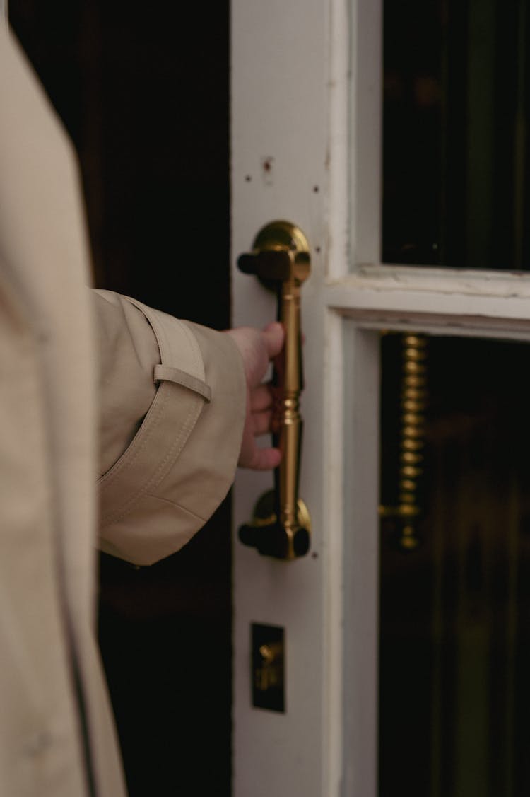 Woman In Beige Raincoat Opening An Old Glass Door