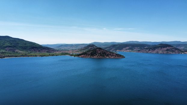 Aerial view of a tranquil lake surrounded by scenic hills in Clermont-l'Hérault, Occitanie, France.
