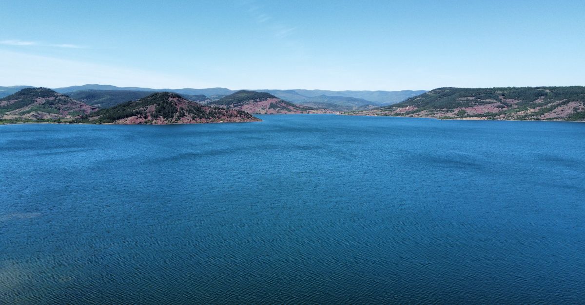 A breathtaking aerial view of a serene lake surrounded by hills in Clermont-l'Hérault, Occitanie, France.