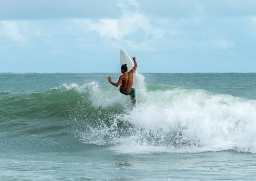 Man Riding Surfboard On Body Of Water