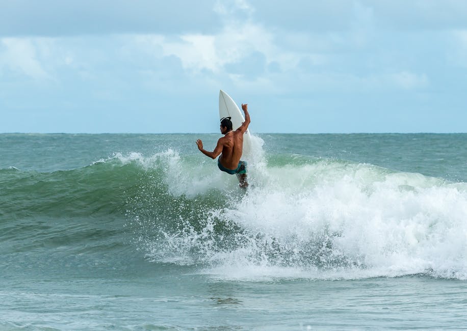 A skilled surfer performs a maneuver on a wave, showcasing athleticism and thrill.