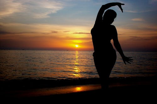 Kostenlos Schattenbild Der Stehenden Frau An Der Küste Während Des Sonnenuntergangs Stock-Foto
