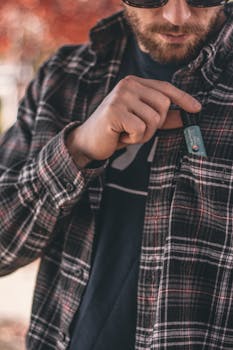 Close-up of a man putting a CBD product into his shirt pocket on a fall day.