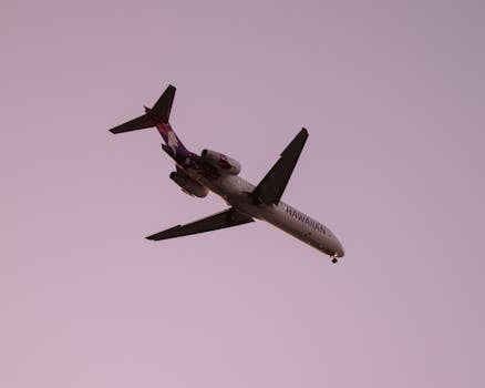 Hawaiian airline plane captured flying against a clear dusk sky in Kailua-Kona, Hawaii.