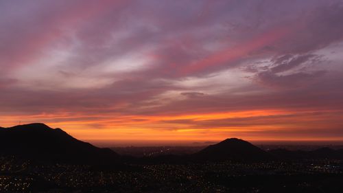 Free Dramatic sunset over Lima, Peru, with striking mountain silhouettes and city lights. Stock Photo